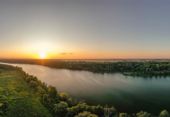 Photo of Fanshawe Lake with Sun rising over the trees in the background.